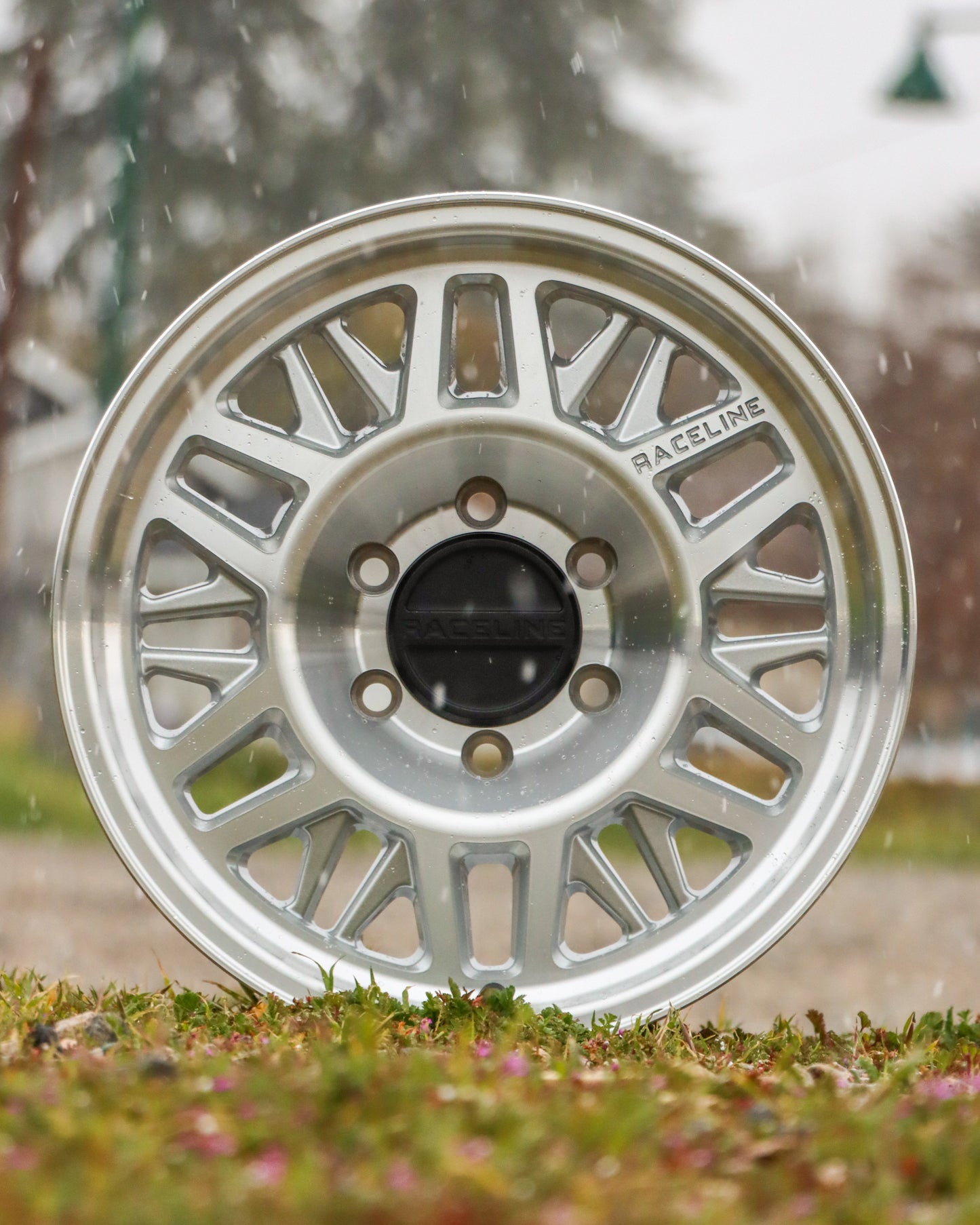 Raceline ryno tr wheel in a machined finish, sitting in a field.