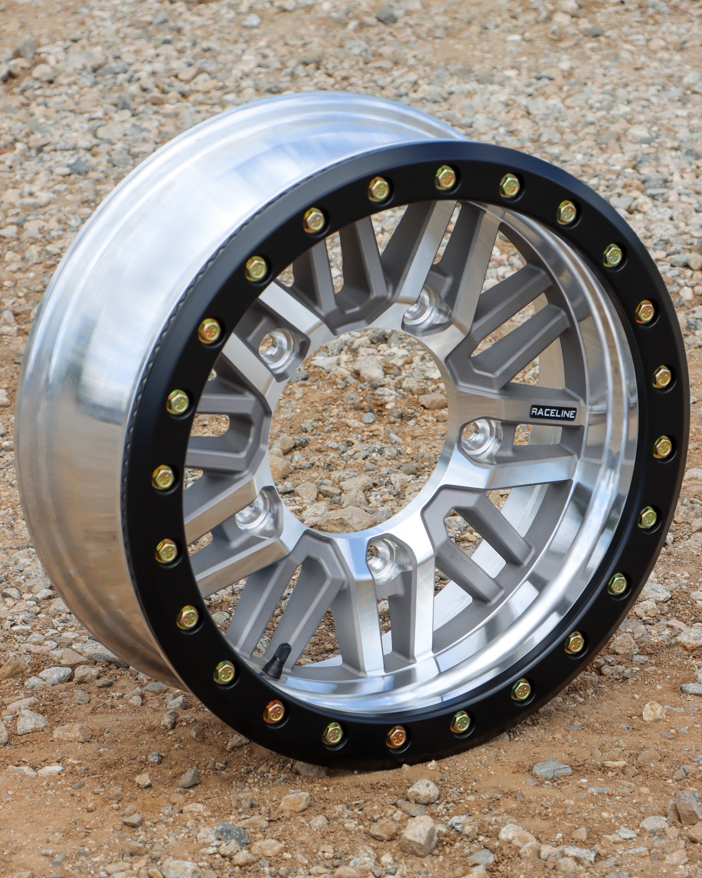 topside view of the raceline ryno buggy wheel in a machined with black lip finish sitting on gravel.