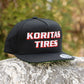 Koritas Tires Classic Snapback Sitting on a rock.