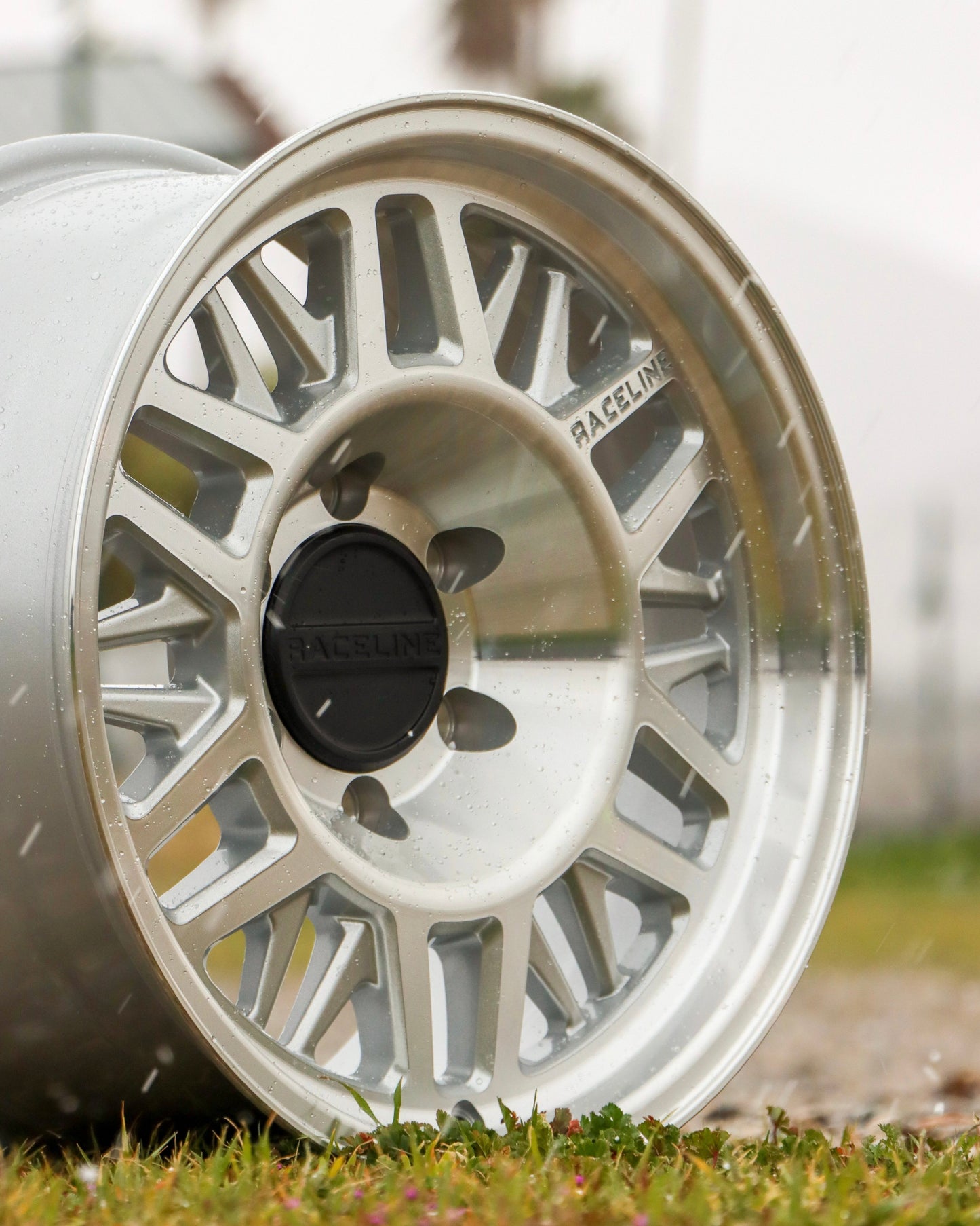 Raceline ryno tr wheel in a machined finish, sitting in a field.