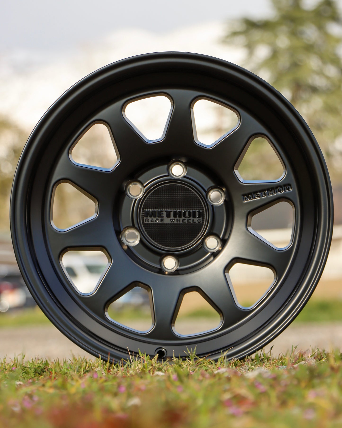 Method mr316 in a matte black finish sitting in a field.