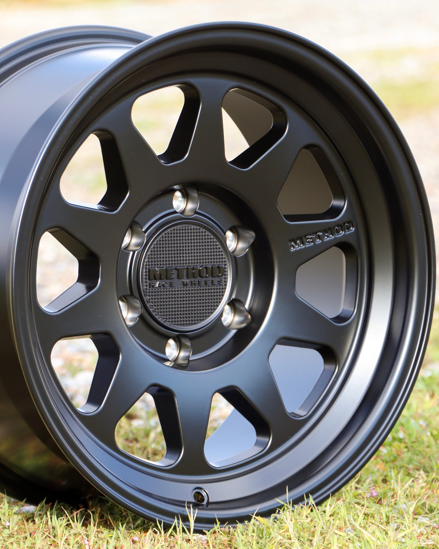 Method mr316 in a matte black finish sitting in a field.