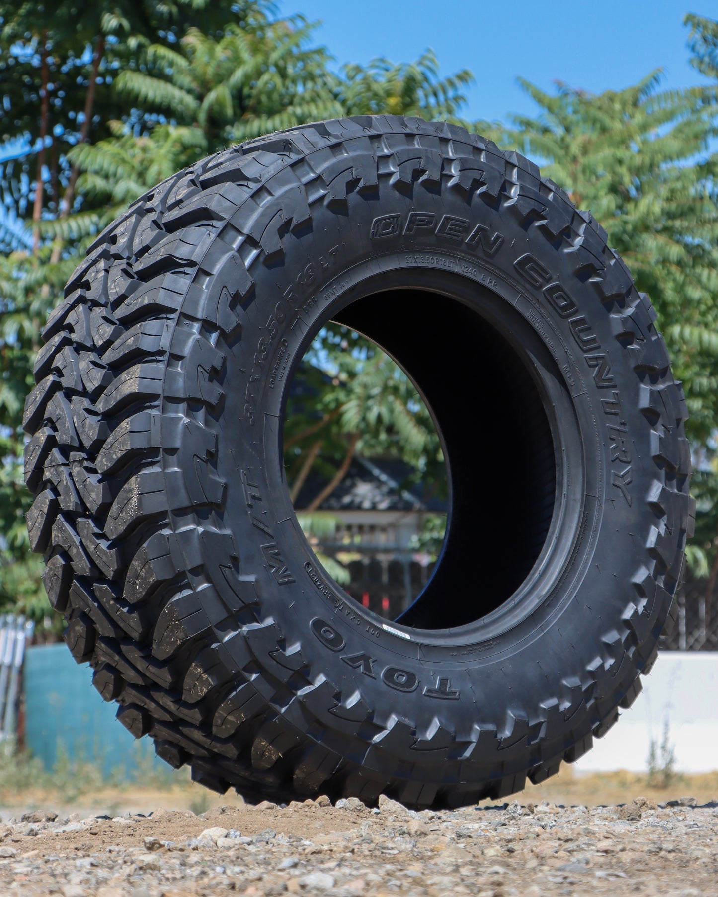 Toyo Open Country M/T sitting on some gravel with trees in the background.