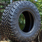 Nitto Trail Grappler sitting on the ground in the dirt with trees in the background.