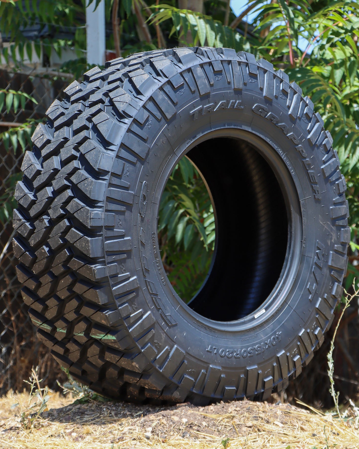 Nitto Trail Grappler sitting on the ground in the dirt with trees in the background.