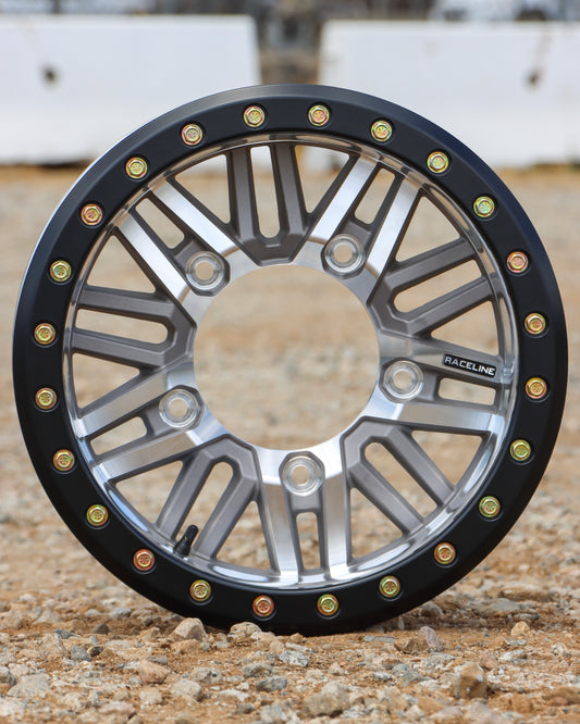 Raceline Ryno Beadlock Buggy Wheel in a machined with black ring finish sitting on gravel.