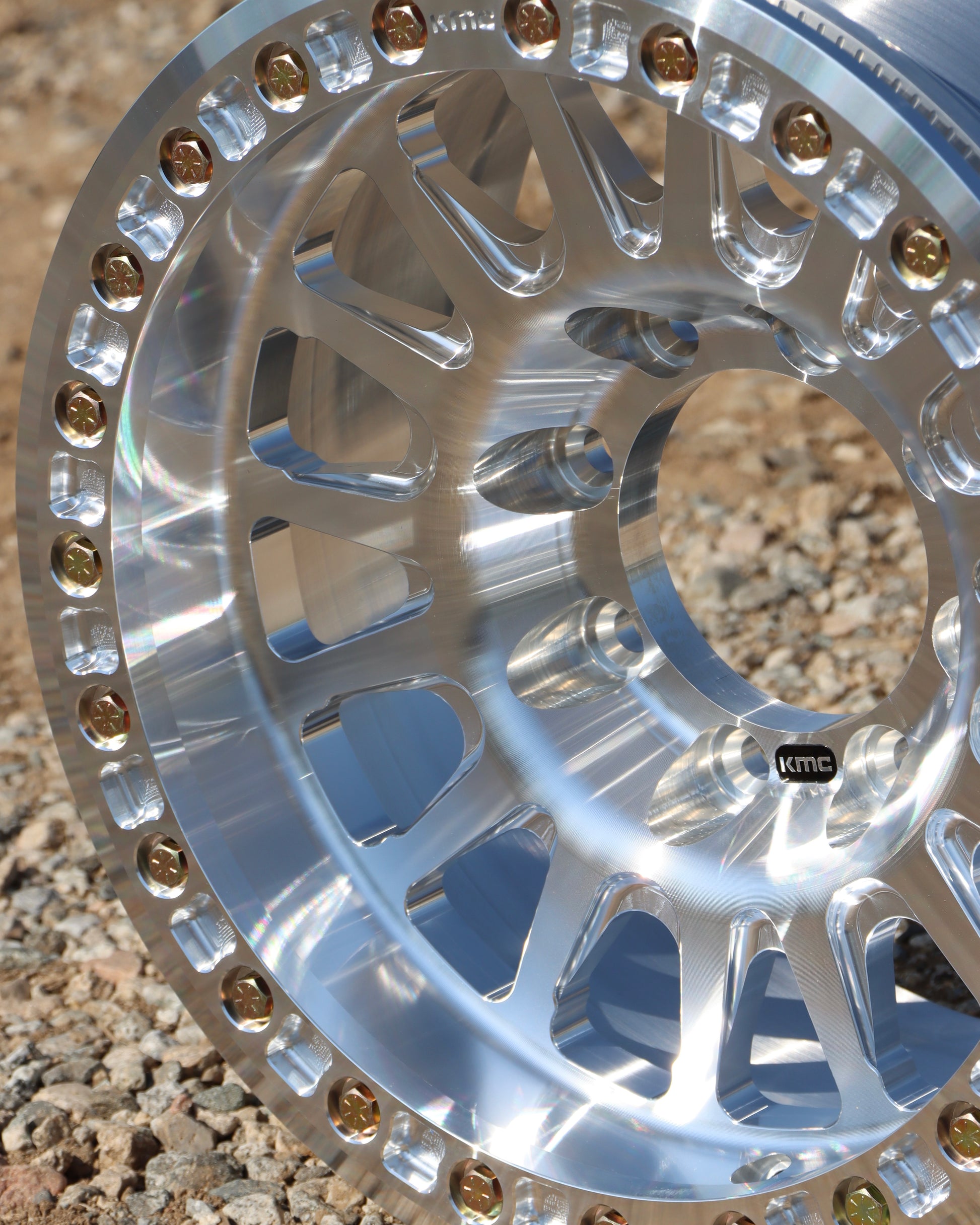 Close-up of the kmc impact forged bead lock wheel on gravel.