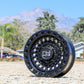 Black Rhino Sentinel Wheel in a matte black finish, on the ground with a majestic mountain background.