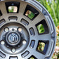 Close-up of the icon thrust wheel in the smoked satin black with bushes in the background.