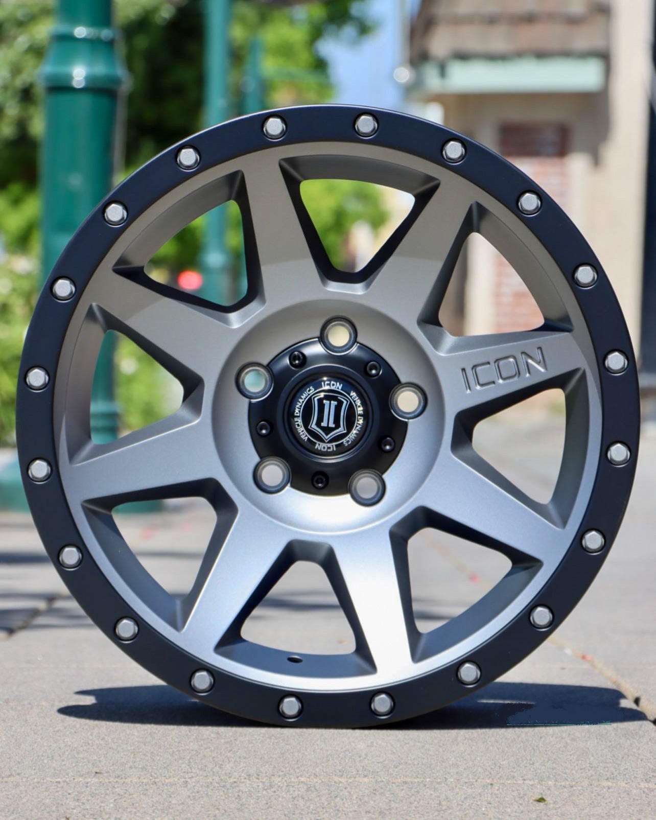 Icon Rebound wheel, in a silver/titanium finish, in the middle of the sidewalk