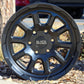 The Black Rhino Chase Wheel in a matte black finish sitting in a planter of woodchips.