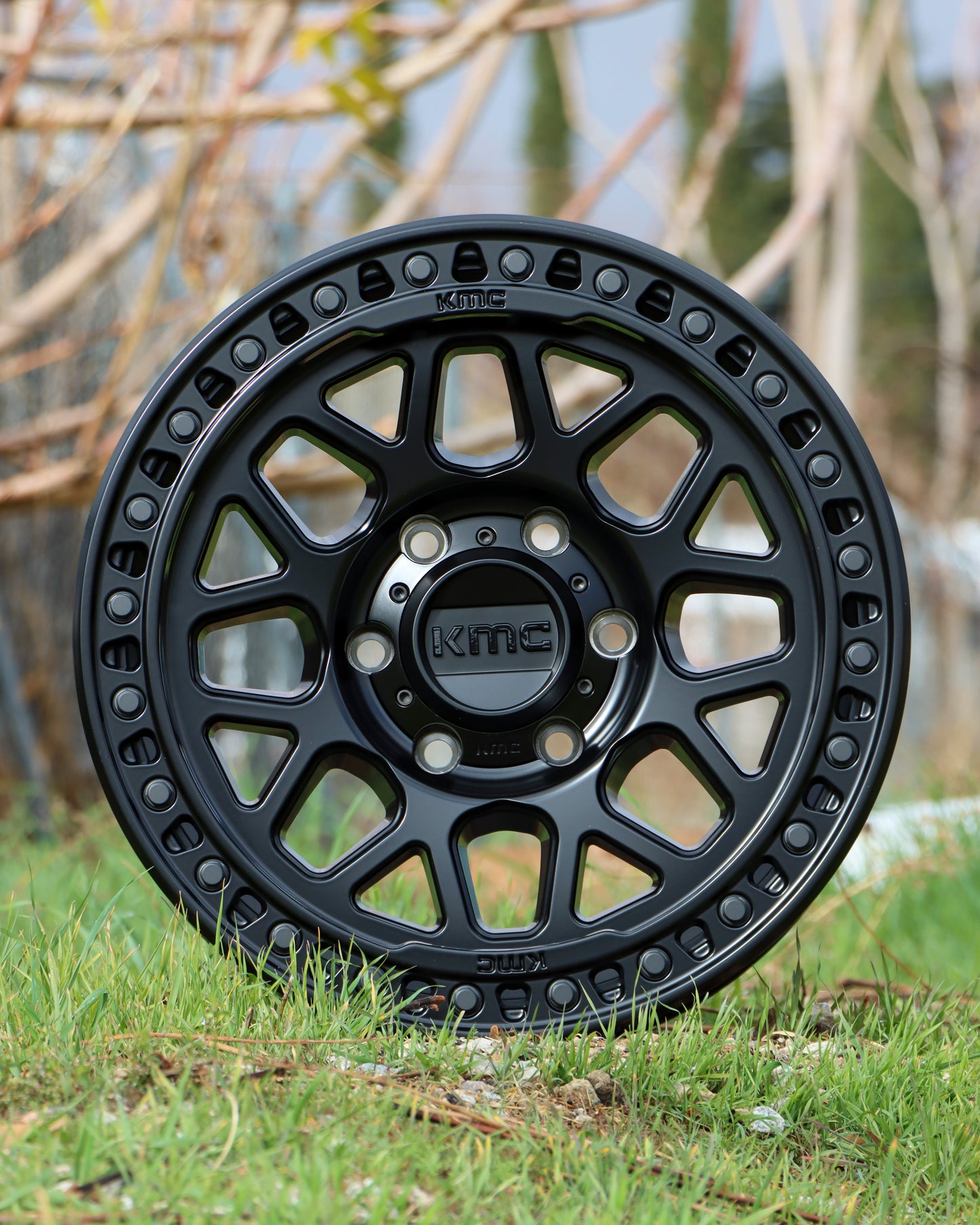 The KMC GRS Wheel in a satin Black Finish sitting on some grass.