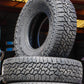 Stack of Falken Wildpeak AT3 tires with one standing up showing the tread and side-wall.