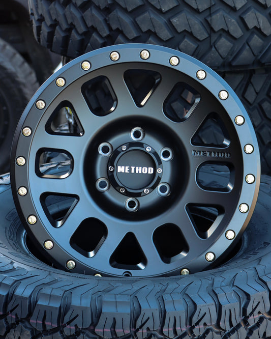 Method MR309 Grid Wheel in a matte black finish, sitting in a tire.