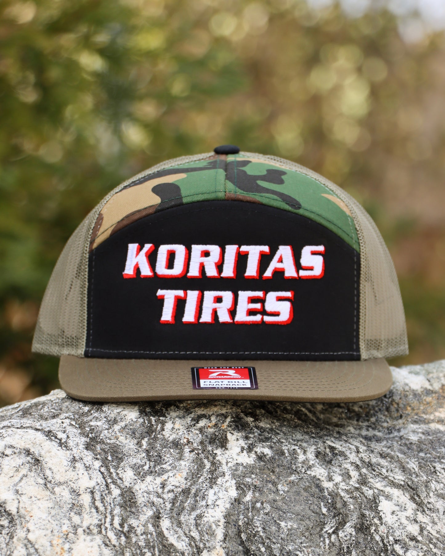 Koritas Tires 7 panel trucker hat sitting on a rock.