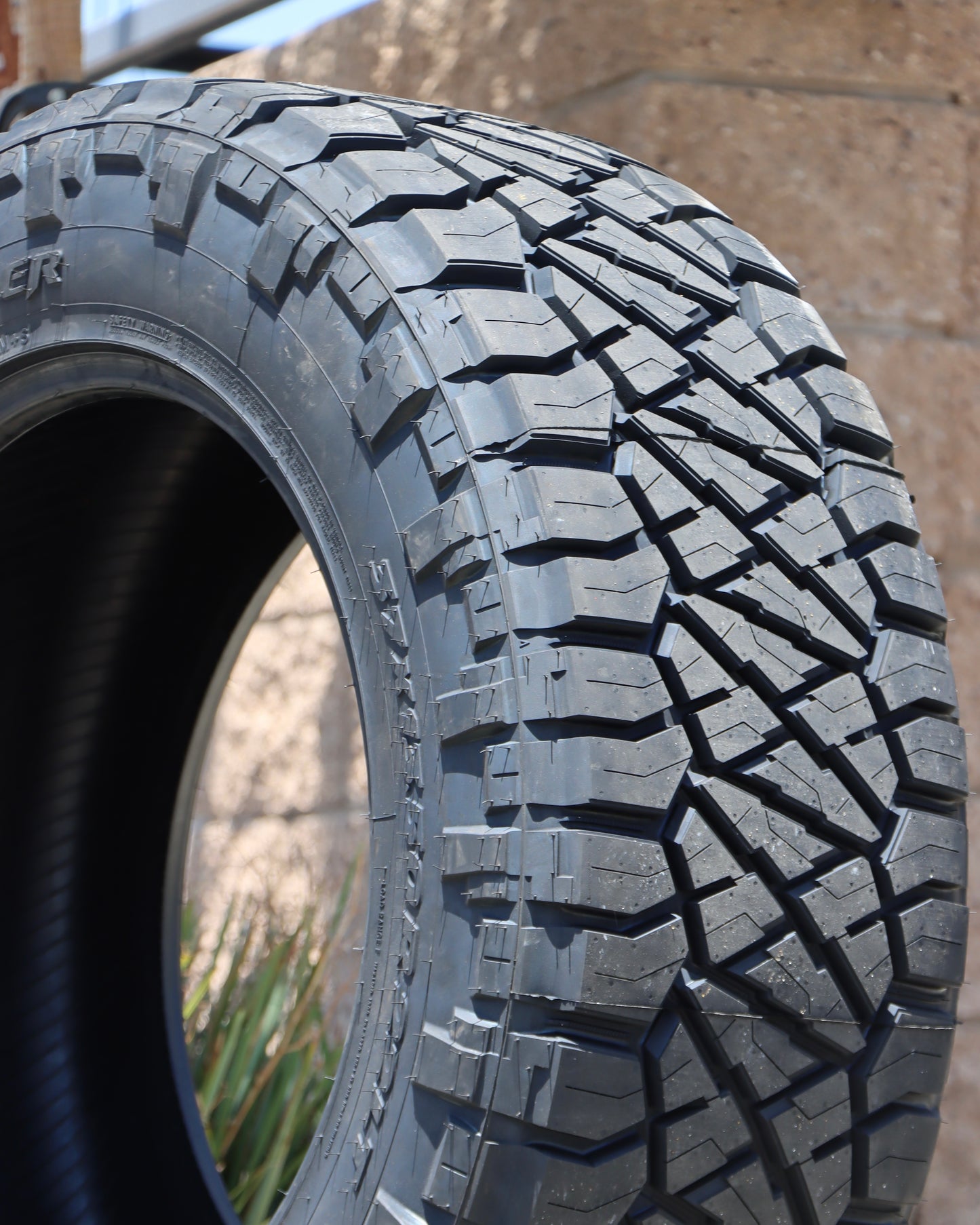 close-up of the nitto ridge grappler showing the tread and sidewall with a brick wall in the background.