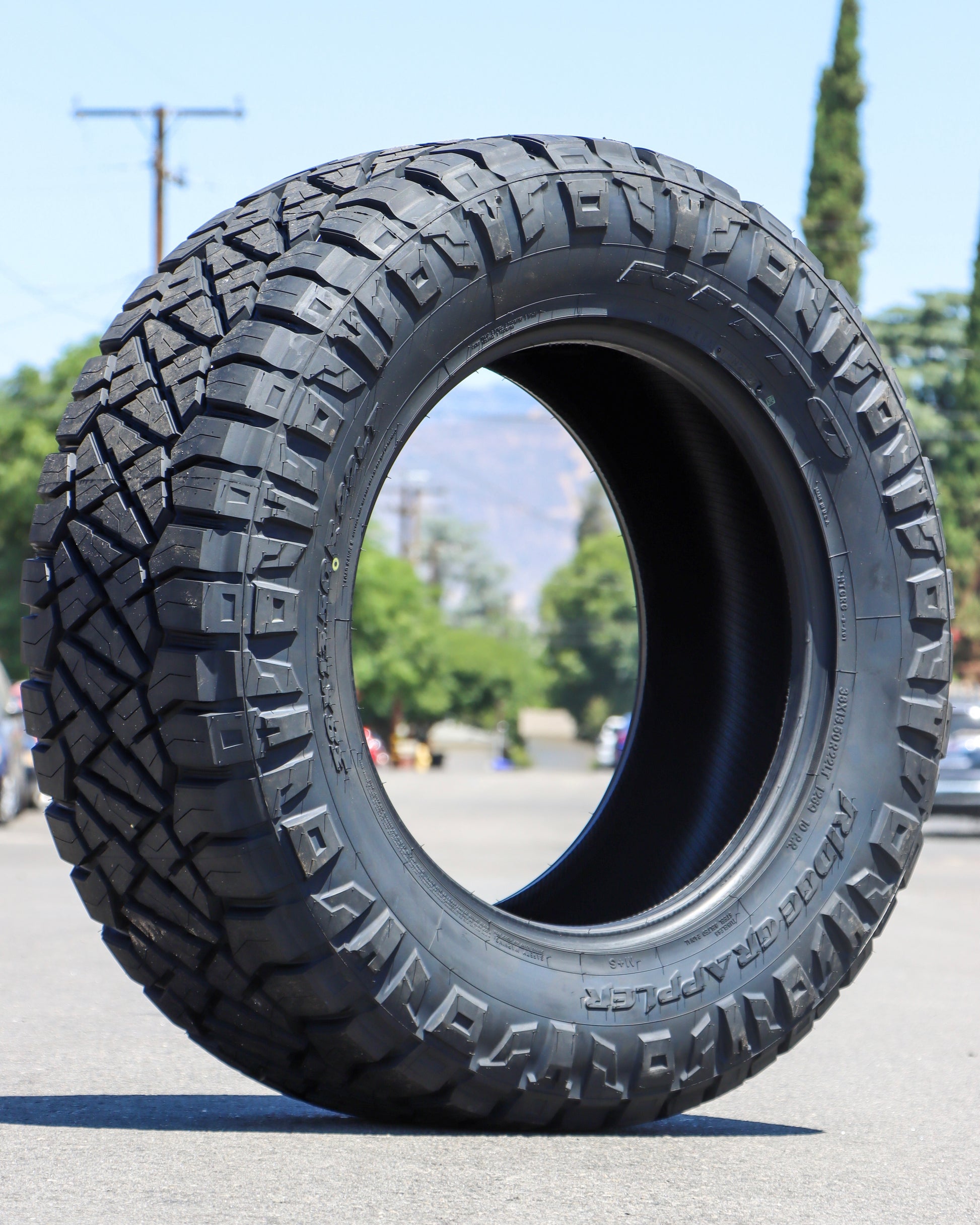 Nitto ridge grappler tire sitting in the middle of the street with the mountains and trees in the background. 