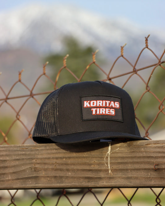 Koritas Tires Trucker Hat Sitting on a fence.