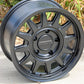 top View of the Raceline Areo Wheel in a matte black finish with bushes in the background.