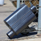 Flowmaster 40 Series Chambered Muffler Leaning against a chain link fence.