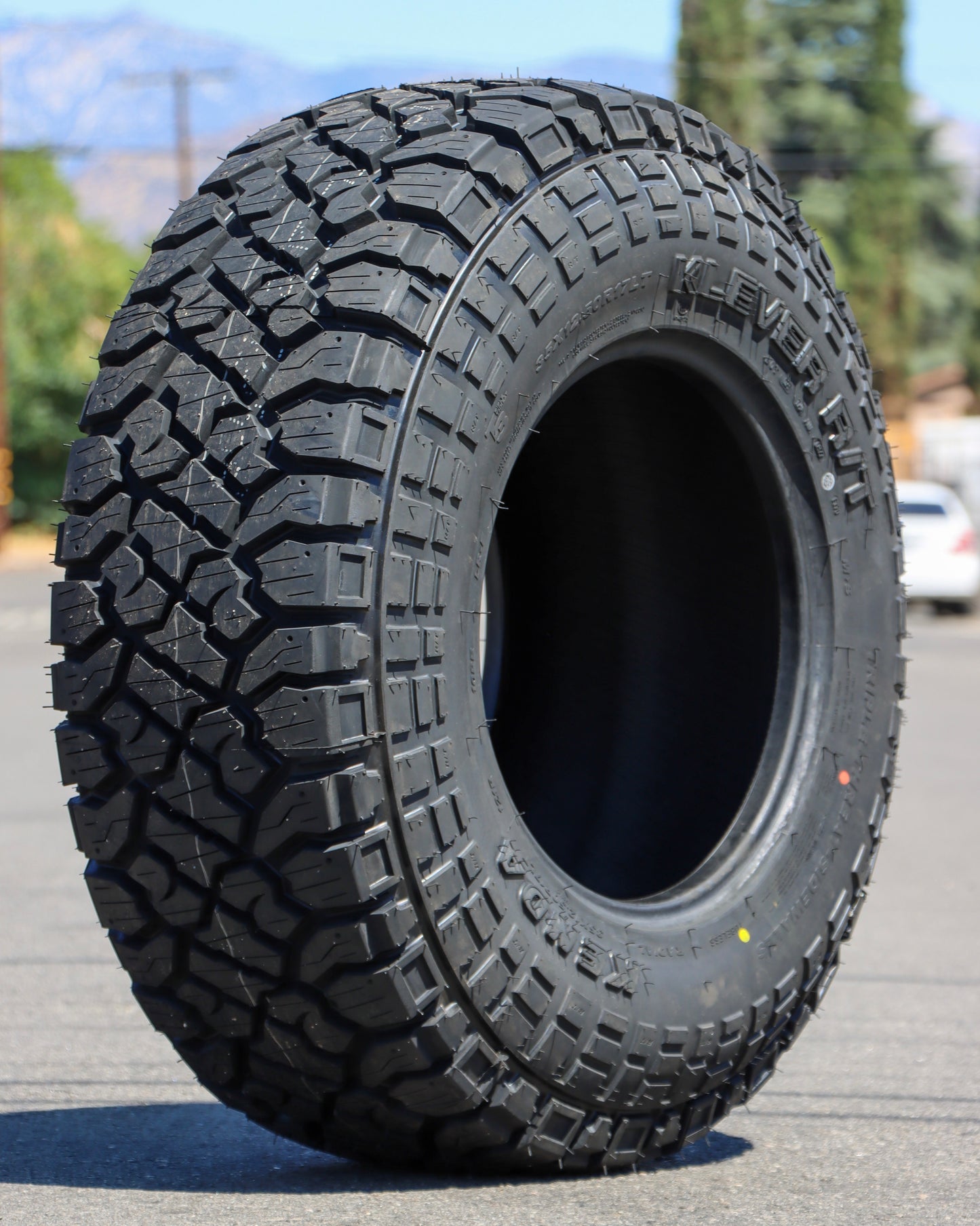 Kenda Klever R/T Tire in the middle of the street at an angle where you can see the tread and also the sidewall.