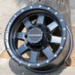 Raceline Defender wheel in a matte black finish leaning up against a palm tree.