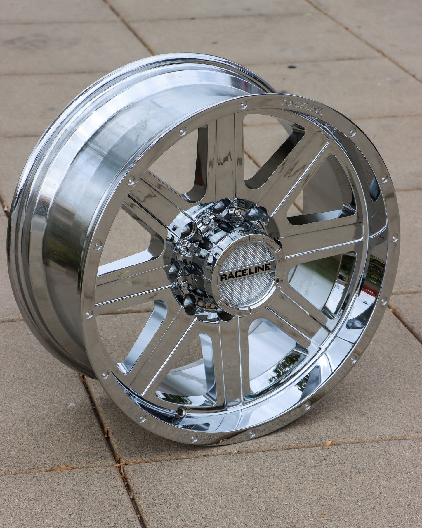 topside view the raceline hostage wheel in a chrome finish on the sidewalk.