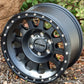 Angled view of the Method MR315 wheel in a matte black finish, sitting in some wood chips next to a bush.