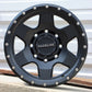 Raceline Boost wheel in a matte black finish sitting on some concrete with a metal sheet in the background.